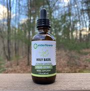 Bottle of Elderflower Botanicals Holy Basil liquid extract on a wooden surface with a forest background
