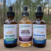 Three bottles of Elderflower Botanicals liquid extracts, immune essentials bundle on a wooden surface with a natural background.