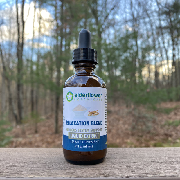 Bottle of Elderflower Remedies Relaxation Blend liquid extract on a wooden surface with a forest background