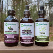 Four bottles of Elderflower Extracts on a wooden surface with a blurred natural background
