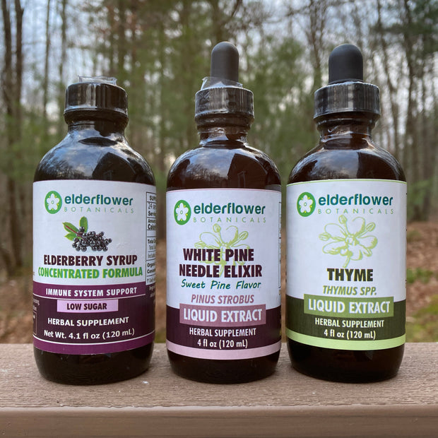 Four bottles of Elderflower Extracts on a wooden surface with a blurred natural background