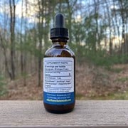 Bottle of supplement with dropper on a wooden surface outdoors