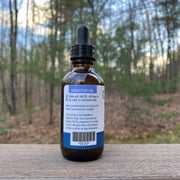 Bottle with dropper on a wooden surface with a forest background