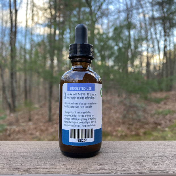 Bottle with dropper on a wooden surface with a forest background