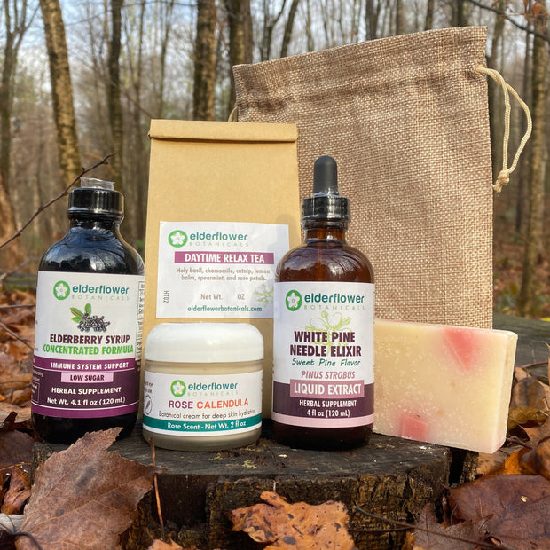 Collection of natural products including bottles, a box, and a bag on a log with a forest background.